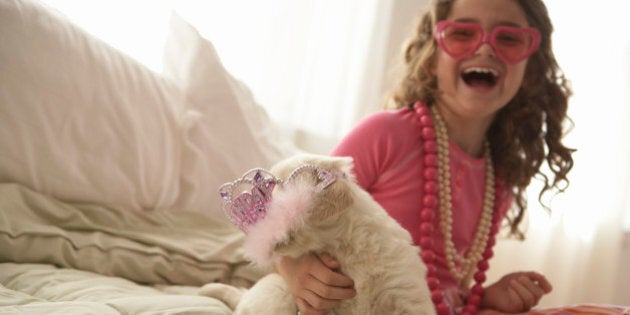 Young girl (8-10) with dog on bed, smiling