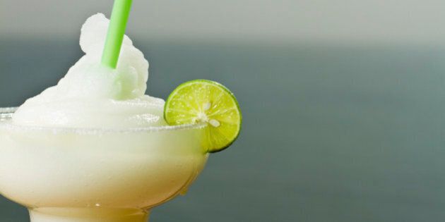 Frozen Margarita with lime and straw at a bar by the ocean