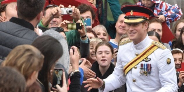 Britain's Prince Harry (C) braves the rain to shake hands with onlookers after laying a wreath at the Australian War Memorial in Canberra on April 06, 2015. Harry arrived in Canberra ahead of a one-month attachment with the Australian Army, as he moves towards his retirement from the British military. AFP PHOTO / MARK GRAHAM (Photo credit should read MARK GRAHAM/AFP/Getty Images)