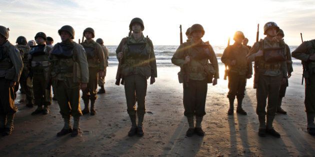 A group of military enthusiasts stand on Omaha Beach in Vierville sur Mer, western France , Friday June 6, 2014. World leaders and dignitaries including President Barack Obama and Queen Elizabeth II will gather to honor the more than 150,000 American, British, Canadian and other Allied D-Day troops who risked and gave their lives to defeat Adolf Hitler's Third Reich. (AP Photo/Thibault Camus)
