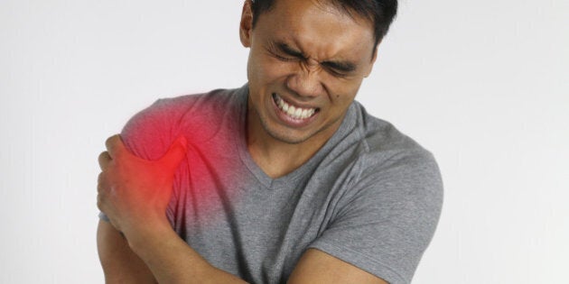 young man suffering from shoulder pain over a white background