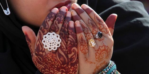 A Pakistani worshipper wearing henna designs on her hands prays at the Badshahi Mosque on the first day of the Muslim holiday of Eid al-Adha, or