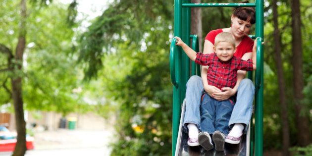 Mother and son on top of slide at playground