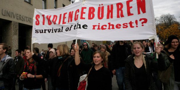 MUNICH, GERMANY - NOVEMBER 17: Students hold a poster reading 'Tuition fees survival of the richest' as they walk past the university of technology during a protest march on November 17, 2009 in Munich, Germany. Following massive protests this summer German students across the country return to the streets to demonstrate against the alleged failings of the educational system. (Photo by Miguel Villagran/Getty Images)