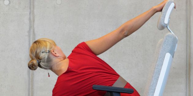 yoga on chair in office - business woman exercising, back view