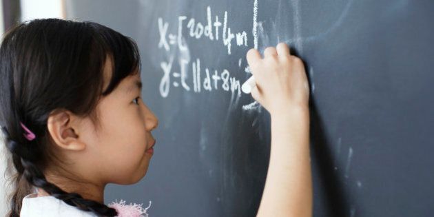 Girl writing on blackboard in classroom