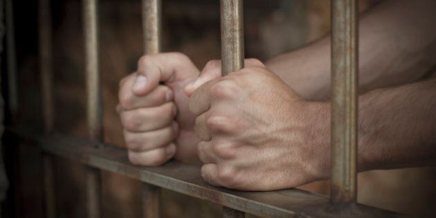 Hispanic man's hands on prison bars