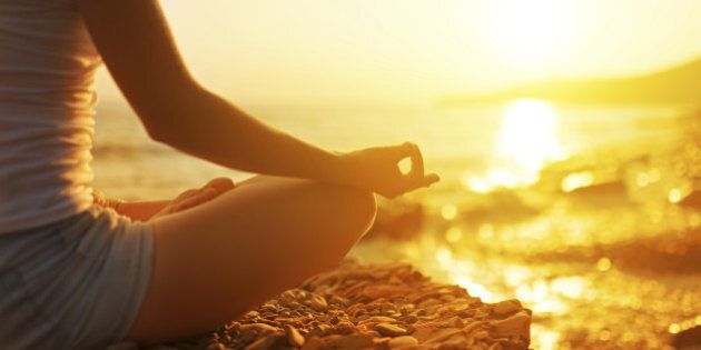 hand of a woman meditating in a yoga pose on the beach