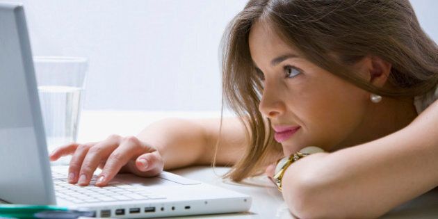 Mixed race businesswoman laying on desk using laptop