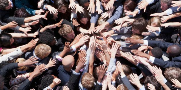 Crowd of business people extending hands in huddle