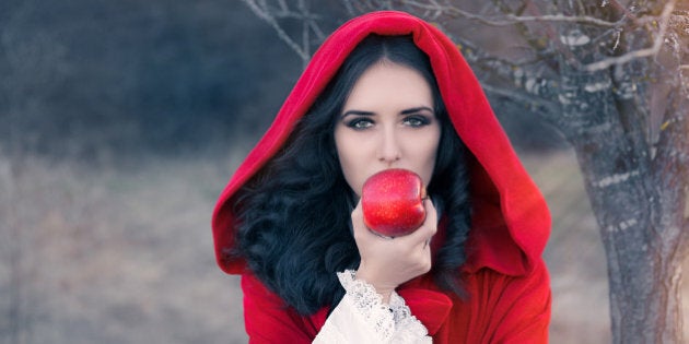 Fairytale image of a beautiful girl wearing a red hood near the forest