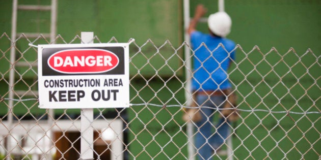 Keep Out sign in front of a carpenter installing windows