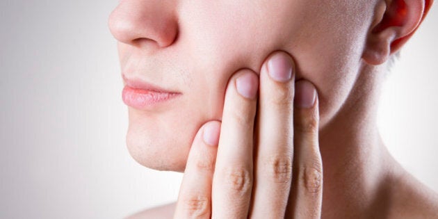 Man with a toothache. Pain in the human body on a gray background