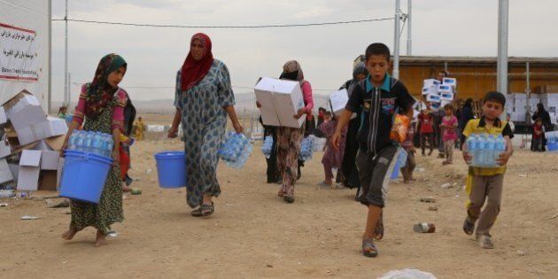 MOSUL, IRAQ - MAY 11: Refugees carry water and food aid distributed by charities after escaping from DAESH, at Makhmur Refugee Camp, in Mosul, Iraq on May 11, 2016. (Photo by Hemn Baban/Anadolu Agency/Getty Images)