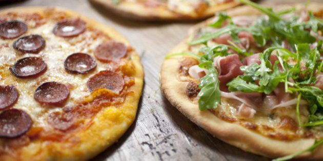Mushroom, pepperoni, margherita, cheese and prosciutto pizzas on a large wooden cutting board