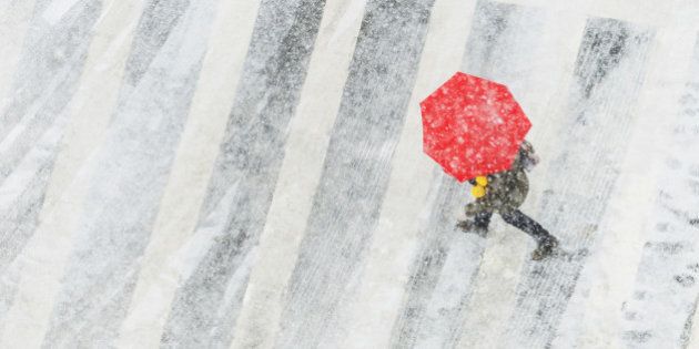 High angle view of person with red umbrella in snowstorm.