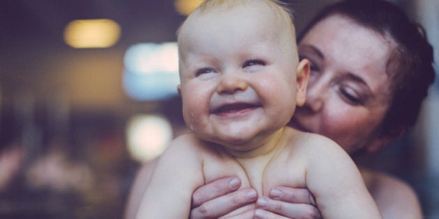 Happy baby boy and mother swimming indoor in a big pool.