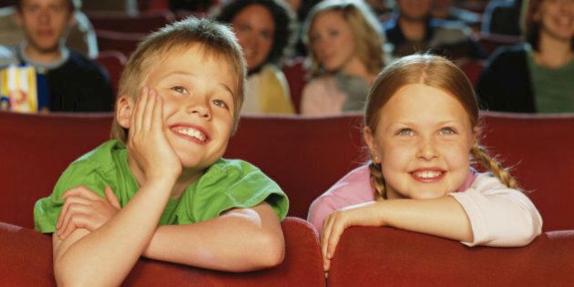 Boy and girl (8-10) in cinema, smiling, close-up