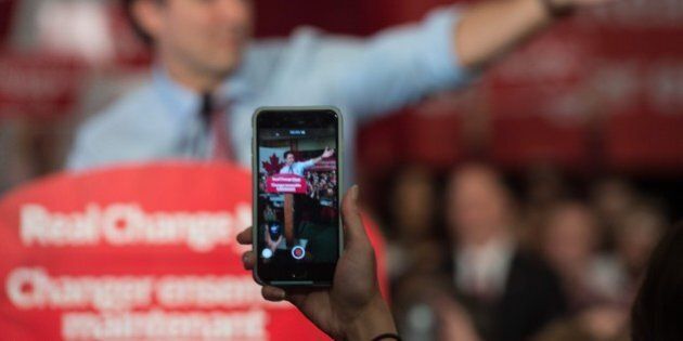 A supporter of Canadian Liberal Party leader Justin Trudeau films him on her smartphone as he speaks at a victory rally in Ottawa on October 20, 2015 after winning the general elections. Liberal leader Justin Trudeau reached out to Canada's traditional allies after winning a landslide election mandate to change tack on global warming and return to the multilateralism sometimes shunned by his predecessor. AFP PHOTO/ NICHOLAS KAMM (Photo credit should read NICHOLAS KAMM/AFP/Getty Images)