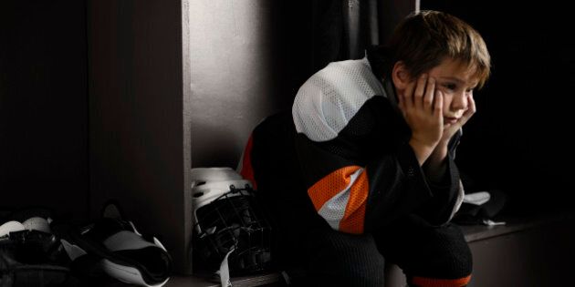 'Portrait of a male youth hockey player sitting in the dressing room tired, after the hockey game.Click on an'