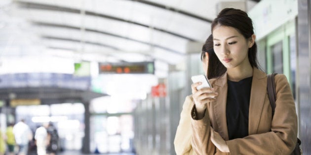 businesswoman checking a smart phone at station