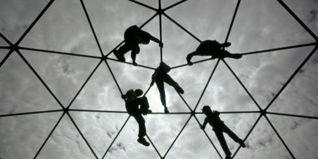 Ethnically diverse young boys and girls silhouetted against the sky while playing and climbing together on a playground Jungle Jim.