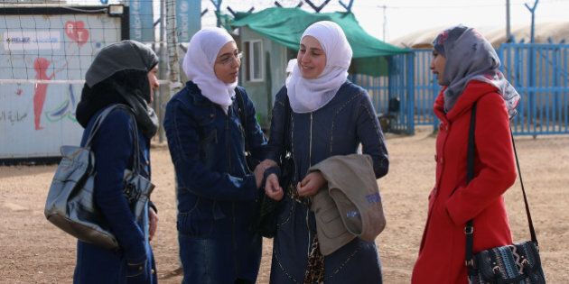 In this Thursday, Jan. 21, 2016 photo, four young Syrian women stand outside a remedial education center in the Zaatari refugee camp near Mafraq, Jordan. The remedial classes are intended for students who need help keeping up in school, including those who missed classes due to the civil war in Syria. (AP Photo/Raad Adayleh)