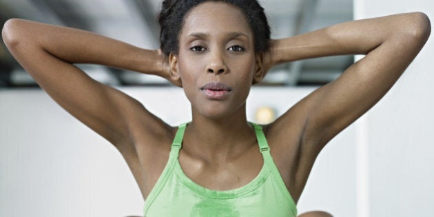 young african american woman in green sportswear exercising abdominals in fitness club, looking at camera. Horizontal shape, front view, waist up