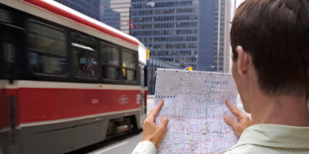 Man holding map standing on city street, Financial District, Toronto, Ontario