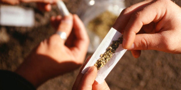 People rolling joints on street, close-up of hands