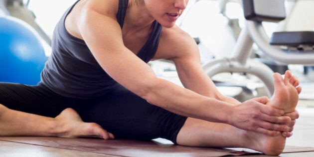 Hispanic woman stretching in gym