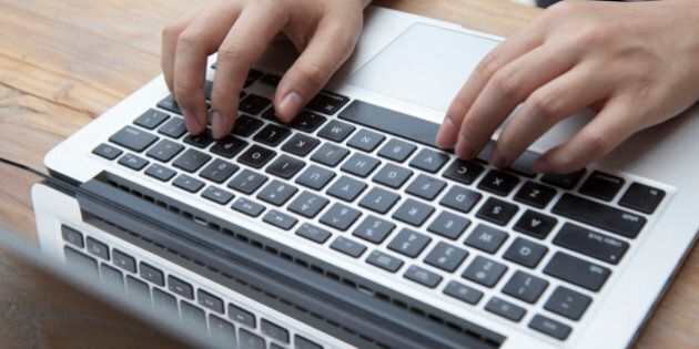 Two hands typing on a keyboard of a laptop computer.