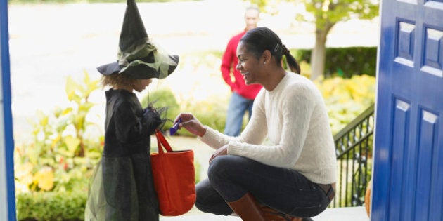 African woman giving candy to trick or treater