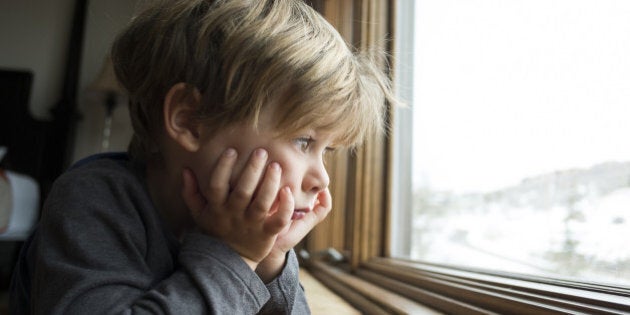 4 year old blonde boy looking out large window.