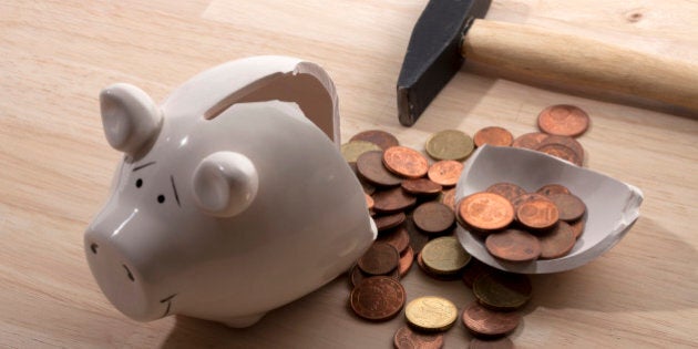 A hammer lying next to a broken piggy bank with Euro coins spilling out