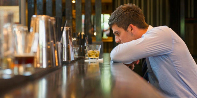 Lonely Hispanic businessman sitting at bar