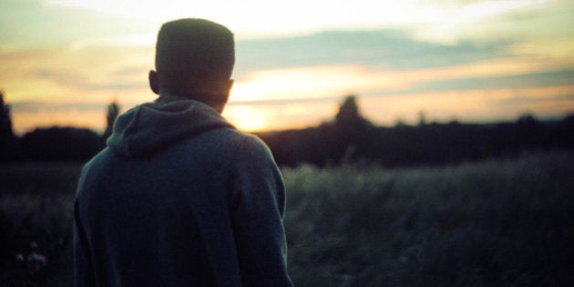 Young man staring into the distance watching the sun set