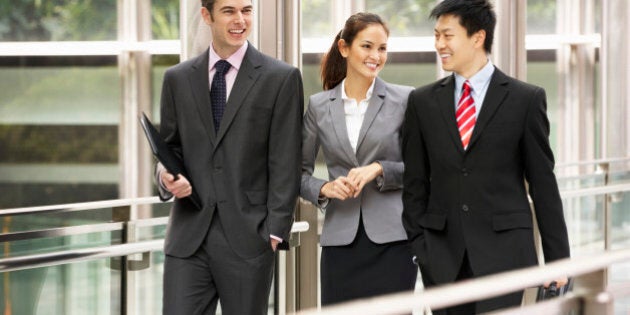 Three Business Colleagues Having Discussion Whilst Walking Outside Office