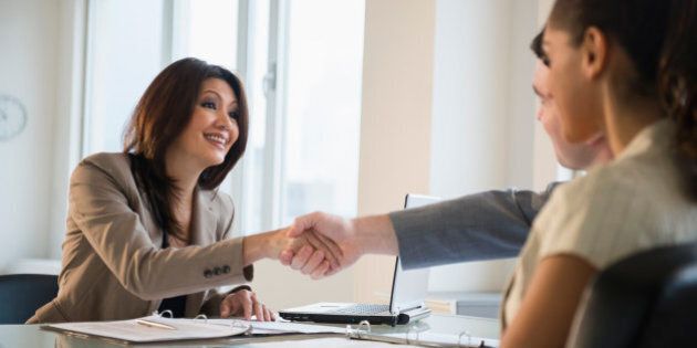Businesswoman shaking hands with clients at desk