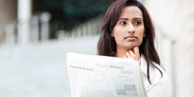 Indian businesswoman reading newspaper outdoors