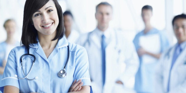 Portrait of a young nurse with her team in the background