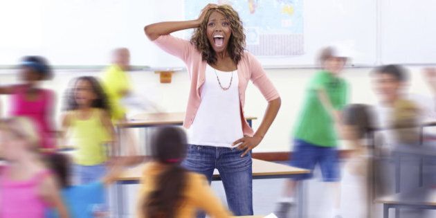 Portrait of a young teacher shouting as her students run around her