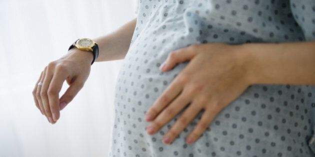 Pregnant Caucasian woman timing contractions in hospital