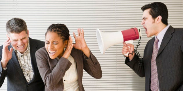 Businessman shouting through bullhorn at co-workers