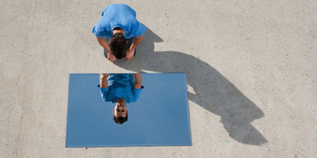 Man kneeling on ground with mirror and reflection