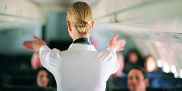 Rear View of Air Stewardess Explaining Aeroplane Safety to Passengers