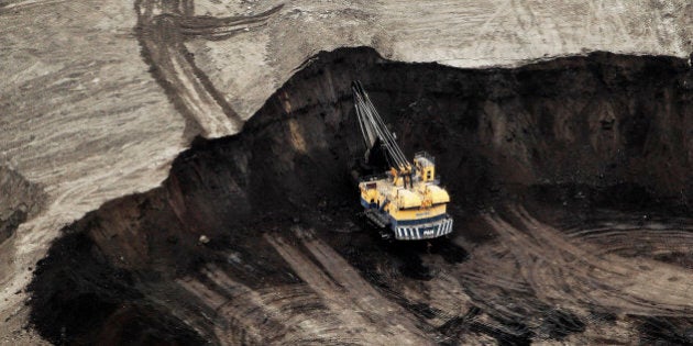 FILE PHOTO: A machine works at the Suncor Energy Inc. mine in this aerial photograph taken above the Athabasca Oil Sands near Fort McMurray, Alberta, Canada, on Wednesday, June 19, 2014. Oil extended losses below $60 a barrel amid speculation that OPEC's biggest members will defend market share against U.S. shale producers. Photographer: Ben Nelms/Bloomberg via Getty Images