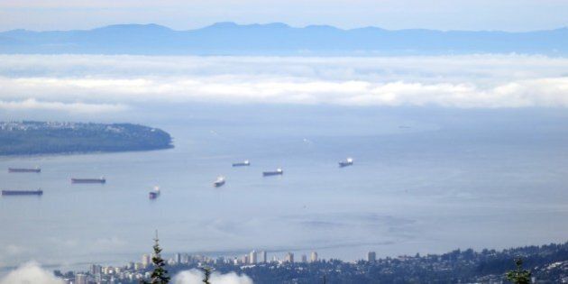 View from Grouse Mountain, showing North Vancouver in the foreground, then freighters moored in English Bay; the tip of UBC peninsula; low cloud over the Strait of Georgia; and the mountains of Vancouver Island in the background.