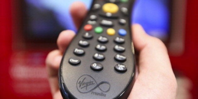 A man holds a television remote control unit for a Virgin Media set top box in this arranged photograph at the company's store on Oxford Street in London, U.K., on Wednesday, Feb. 6, 2013. Billionaire John Malone's Liberty Global Inc. agreed to acquire Virgin Media, Britain's second-largest pay-TV provider, in a $16 billion cash-and-stock transaction announced in the U.S. yesterday. Photographer: Chris Ratcliffe/Bloomberg via Getty Images