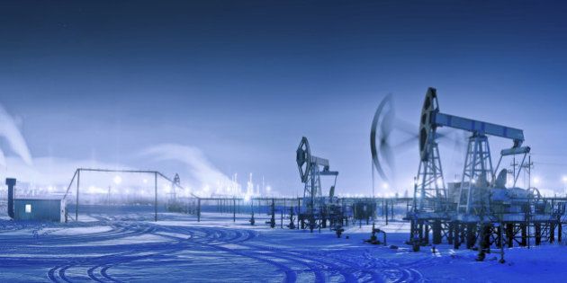 Oil and gas industry. Panoramic of a pumpjack and oil refinery in the winter with snow. Night view.